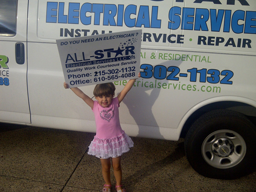 A little girl holding up a sign for All Star Electrical Services