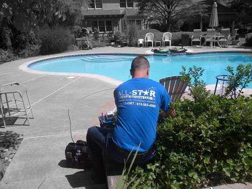 An electrician installing landscape lights by a pool