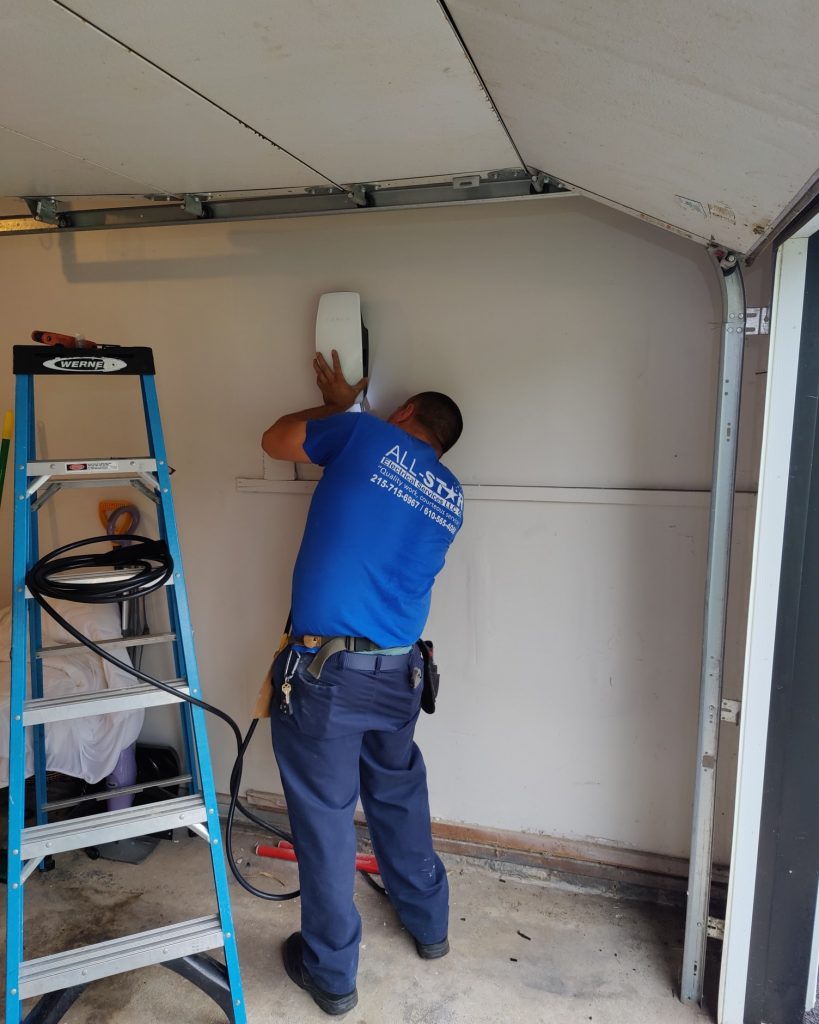 A technician from All Star Electrical Services, LLC installing an EV charging station in a garage