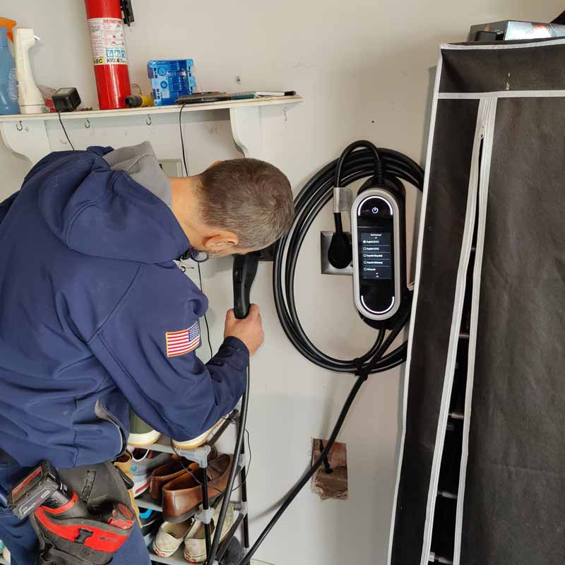 An electrician installing an EV charging station in a garage